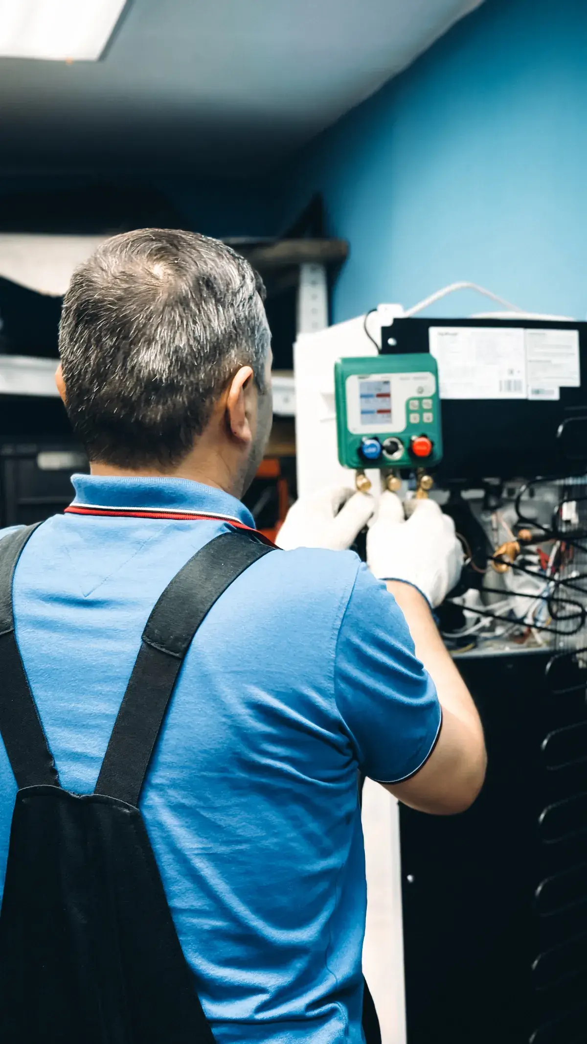 Air conditioning technician checking refrigerant pressures during a ducted installation