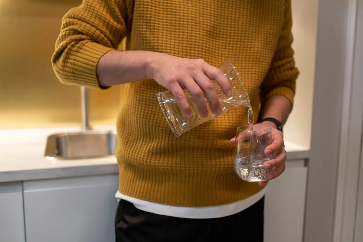 Filtered drinking water poured from a jug in a home kitchen