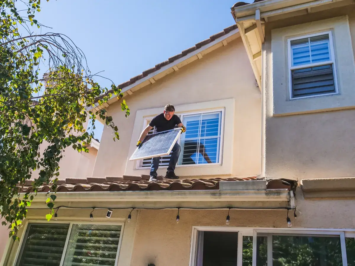 Installer fitting a solar panel to a residential roof